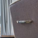Close-up of a chair with metal handle and fabric upholstery near window