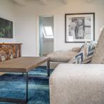 Living room with sofa, coffee table, and wall art. TV mounted on wall.