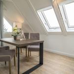Dining room with table, chairs, and skylights. Wooden floor and light walls.