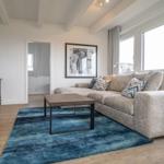 Living room with sofa, rug, and TV mounted on the wall.