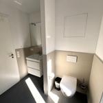 Badezimmer mit Toilette, Waschbecken und Spiegel. Fliesenboden und Wandverkleidung.