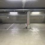 Untertageparkplatz mit zwei geparkten Autos und Betonstützen.