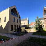 Moderne Wohnhäuser mit Balkonen und gepflasterten Wegen in ruhiger Wohngegend.