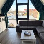 Wohnzimmer mit Sofa, Tisch und Fenster mit Blick auf Dächer.