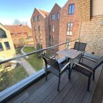 Terrasse mit Tisch und Stühlen, Blick auf Wohnhäuser und Grünfläche.