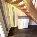 Treppenhaus mit Holztreppen und weißem Schrank unter der Treppe.