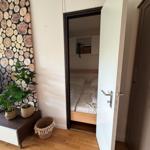 Ein Raum mit Holzfußboden, einer Tür zum Schlafzimmer und einer Wand mit Holzschliff-Motiv.