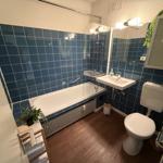 Badezimmer mit Badewanne, Waschbecken und Toilette. Blaue Fliesen an den Wänden.