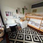 Ein Schlafzimmer mit Doppelbett, Schreibtisch und Regal mit Dekoration.