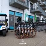 Viele Fahrräder und E-Bikes stehen vor einem Gebäude mit Balkonen und einem Golfcart.