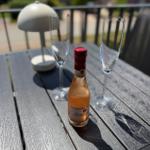 Auf dem Balkon steht ein Tisch mit einer Flasche Rosé, zwei Gläsern und einer Lampe.