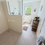 Bad mit Dusche, Toilette und Fenster mit Blick auf Grün.