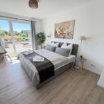 Schlafzimmer mit Doppelbett, Fenster und Wandbild.