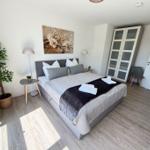 Schlafzimmer mit Bett, Kleiderschrank und Pflanze.