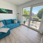 Ein Wohnzimmer mit blauem Sofa, Holzboden und Balkon mit Sitzgelegenheiten.