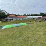 Green playground with slide and climbing frame on grassy area.