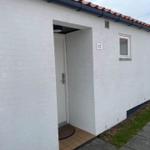 Entrance with door and window on white facade with tiled roof.