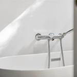 Eine weiße Badewanne mit chromfarbenem Wasserhahn und Duschbrause.