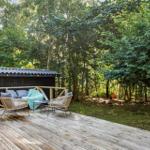 Terrasse mit Sitzgelegenheiten und kleinem Holzhaus im Wald