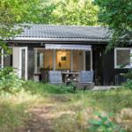 Ein Holzhaus mit Terrasse und Sitzgelegenheiten im Grünen.