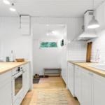 Küche mit Holz Arbeitsfläche, weißen Schränken und Fenster zum Wald.