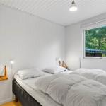 Schlafzimmer mit Bett, Fenster und Wandregal. Holzfußboden und weiße Wände.
