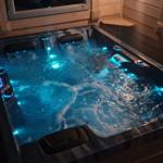 Ein beleuchteter Whirlpool mit blauen Lichtern und Wasserströmungen in einem Holzhaus.