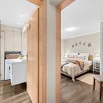 Schlafzimmer mit Bett und Wanddekoration. Nebenraum mit Dusche und Waschmaschine.