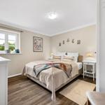 Schlafzimmer mit Bett, Nachttischen und Fenster. Wanddekoration mit BEACH.