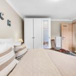 Schlafzimmer mit Bett, Kleiderschrank und Sicht auf Küche.