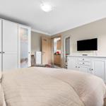 Schlafzimmer mit Bett, Kleiderschrank und Fernseher auf Schrank. Tür führt in Küche.