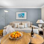 Wohnzimmer mit Sofa, Kissen, Tisch mit Obst und Flasche.