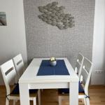 Esszimmer mit weißem Tisch, vier Stühlen und Wanddekoration aus Fischen.