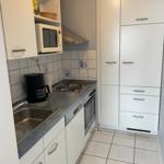 Küche mit weißen Schränken, Kochfeld, Spüle und Mikrowelle.