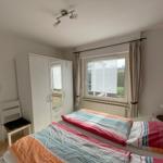 Schlafzimmer mit Doppelbett, Kleiderschrank und Fenster mit Vorhängen.