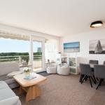 Wohn- und Essbereich mit Balkon, Sofa, Esstisch und Wandbildern.