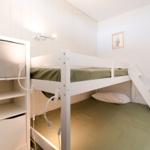 Zimmer mit Doppelstockbett, Schrank und Wandbeleuchtung.