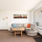Wohnzimmer mit Sofa, Tisch und Blick aufs Wasser.