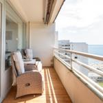 Balkon mit Sitzgelegenheiten und Blick aufs Meer und Strand.
