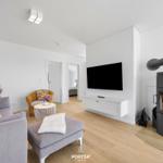Wohnzimmer mit Sofa, Fernseher und Kaminofen auf Holzfußboden.