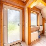 Hölzerner Eingangsbereich mit Glastür und angrenzender Toilettenkabine.