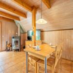 Esszimmer mit Holztisch, Stühlen und Kaminofen. Durchgang zum Garten.