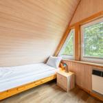 Ein Schlafzimmer mit Holzwand, Bett, Nachttisch und Fenster.