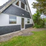 Ein Haus mit grauer Schieferdach und weißer Fassade. Hinterhof mit Gras und Steinweg.