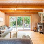 Wohnzimmer mit Holzwand, Sofa, Kamin und Terrassentür.