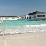 Wellenbad mit moderner Umgebung und Glasfassade. Poolbereich mit Metallgeländer.