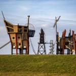 Piratenschiff- und Turmspielplatz auf grüner Wiese unter blauem Himmel