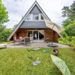 Haus mit Terrasse, Gartenmöbeln und Kinderspielzeug im Gras.