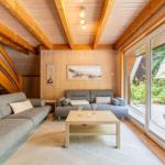 Wohnzimmer mit Holzdecke, Sofa und Blick auf den Garten.