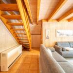 Wohnzimmer mit Holzdecke, Sofa und Treppe zur oberen Etage.